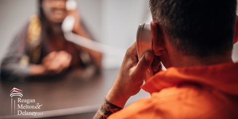 inmate talking on jail phone to woman on other side of partition